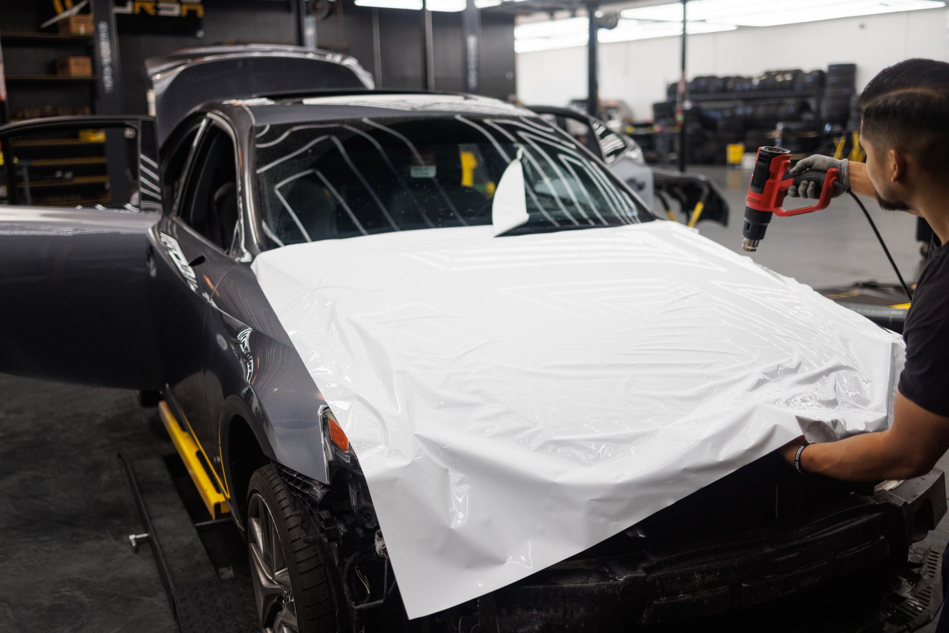 Professional installer applying vinyl wrap to a performance car, illustrating vinyl wrap vs respray UK options
