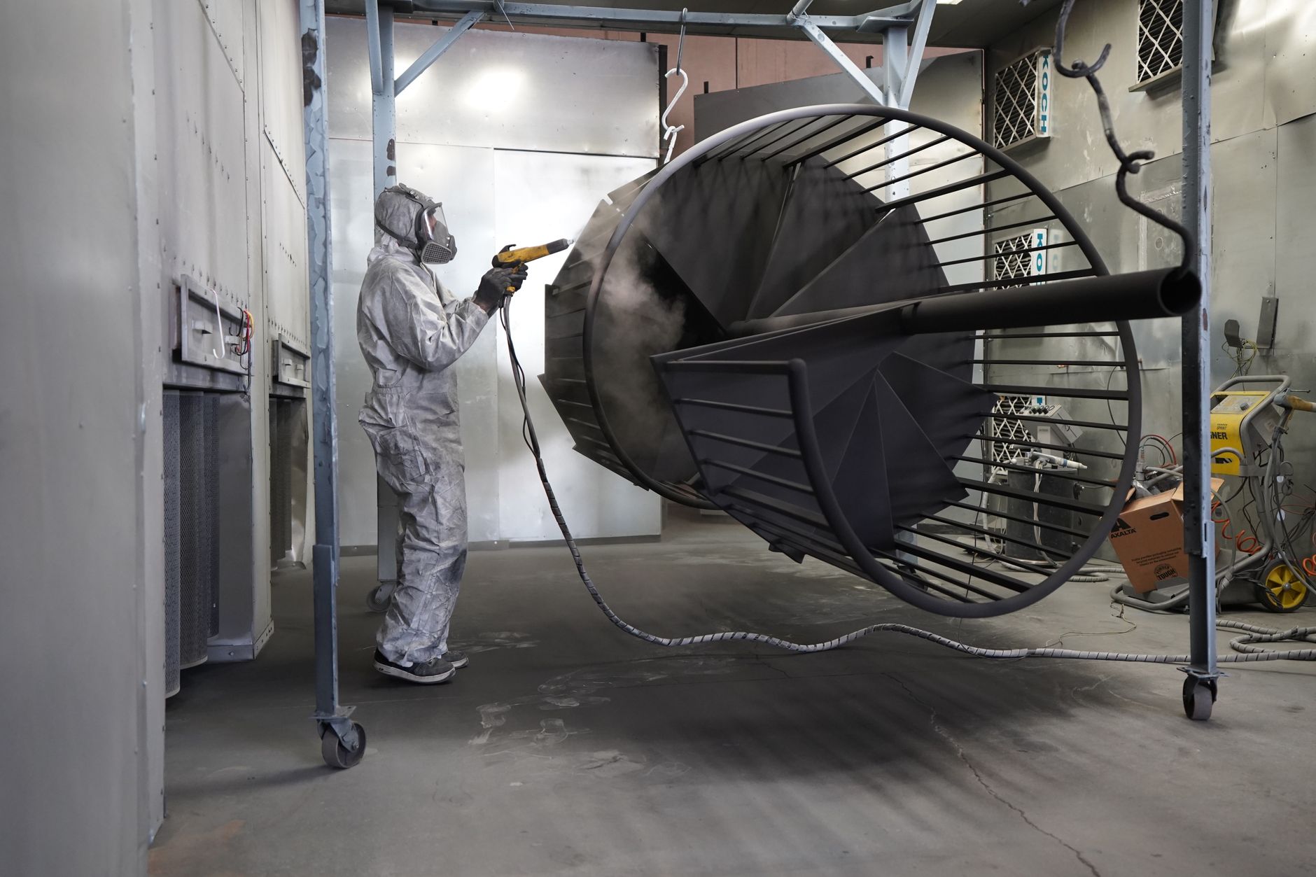 Professional respray technician painting a performance car panel, representing the vinyl wrap vs respray UK debate